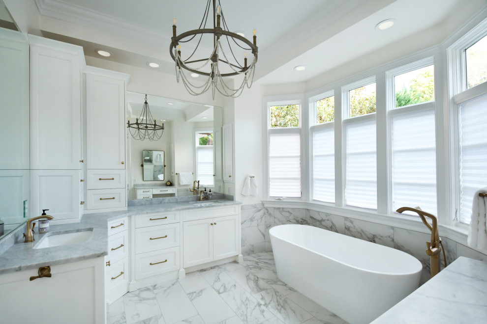Example of a large cottage chic master white tile and porcelain tile double-sink freestanding bathtub design in Other with recessed-panel cabinets, white cabinets, white walls, marble countertops, gray countertops and a built-in vanity