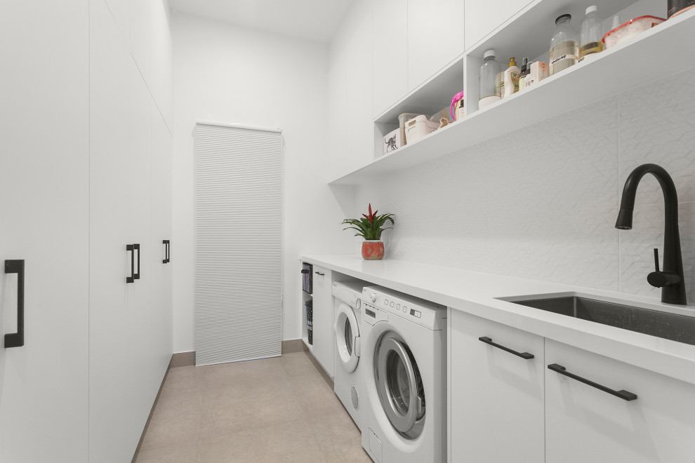 Design ideas for a mid-sized contemporary galley dedicated laundry room in Melbourne with an undermount sink, white cabinets, quartz benchtops, white splashback, ceramic splashback, white walls, ceramic floors, a side-by-side washer and dryer, grey floor and white benchtop.