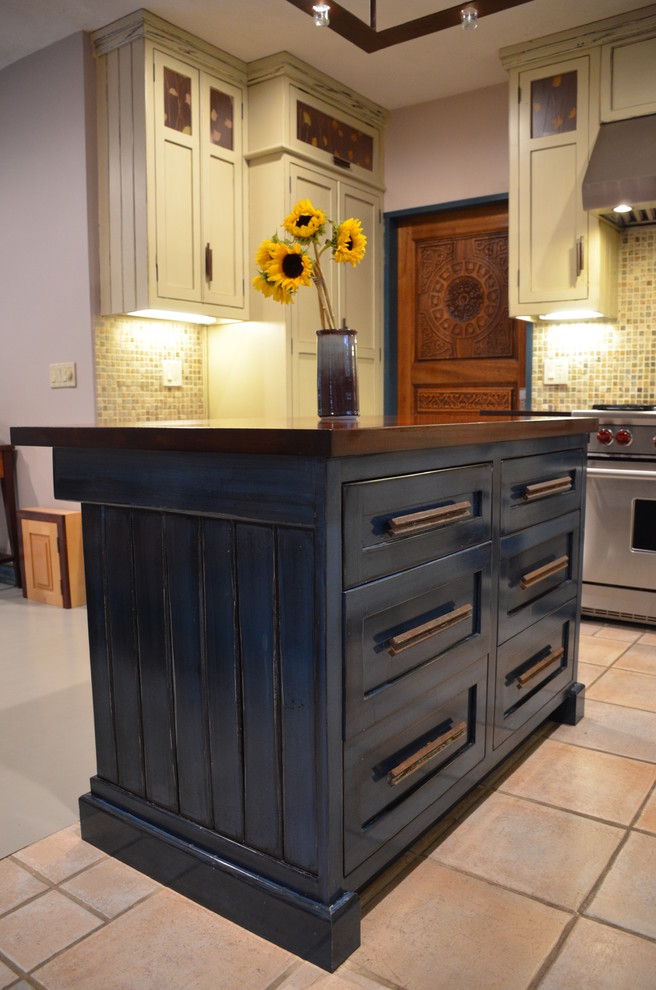 Inspiration for a mid-sized rustic u-shaped ceramic tile eat-in kitchen remodel with a farmhouse sink, recessed-panel cabinets, beige cabinets, wood countertops, multicolored backsplash, stone tile backsplash, stainless steel appliances and an island