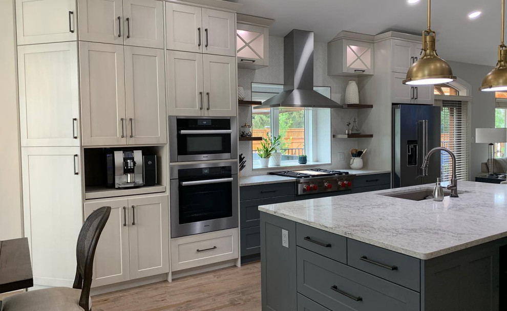 Example of a large transitional galley light wood floor, brown floor and vaulted ceiling eat-in kitchen design with an undermount sink, shaker cabinets, white cabinets, quartzite countertops, white backsplash, ceramic backsplash, stainless steel appliances, an island and white countertops