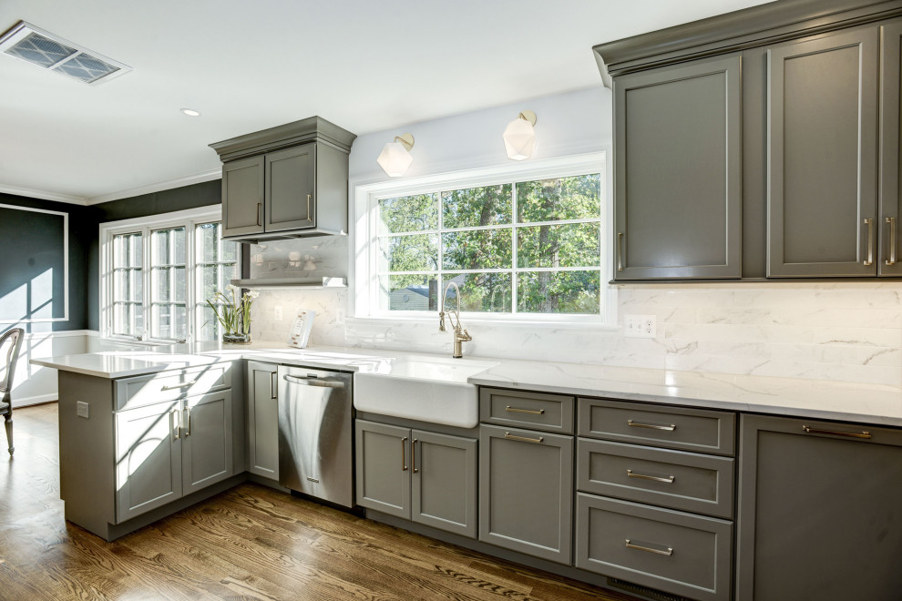 This is an example of a mid-sized transitional u-shaped separate kitchen in DC Metro with grey cabinets, quartz benchtops, white splashback, subway tile splashback, stainless steel appliances, medium hardwood floors, brown floor, white benchtop, a farmhouse sink, shaker cabinets and a peninsula.