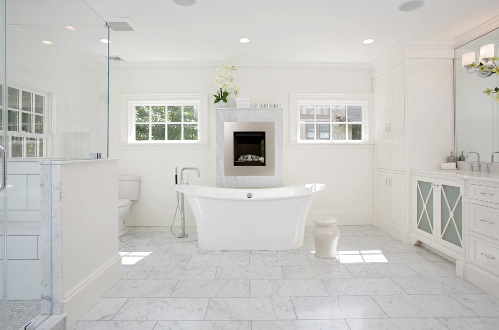 Inspiration for a traditional master bathroom in Boston with recessed-panel cabinets, white cabinets, a freestanding tub, a two-piece toilet, white tile and white walls.