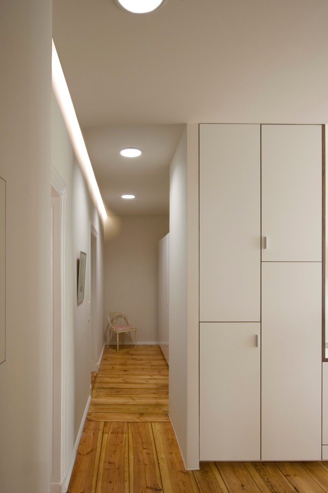 Mittelgroßer Moderner Flur mit weißer Wandfarbe und braunem Holzboden in Berlin