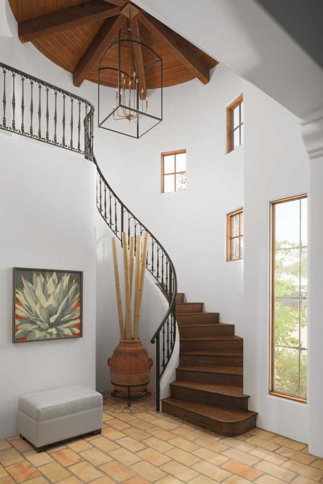 Imagen de escalera curva tradicional renovada grande con escalones de madera, contrahuellas de madera y barandilla de metal