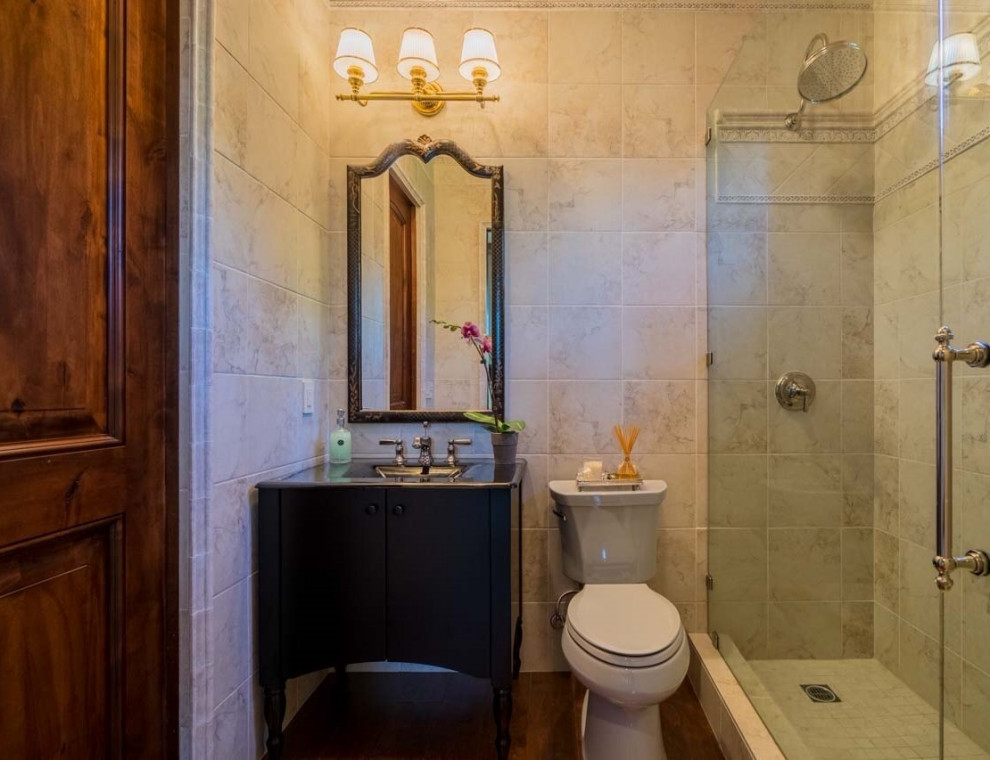 Пример оригинального дизайна: маленькая ванная комната в классическом стиле с плоскими фасадами, черными фасадами, открытым душем, раздельным унитазом, бежевой плиткой, плиткой из известняка, бежевыми стенами, паркетным полом среднего тона, душевой кабиной, монолитной раковиной, столешницей из ламината, коричневым полом, душем с распашными дверями, черной столешницей, тумбой под одну раковину и напольной тумбой для на участке и в саду