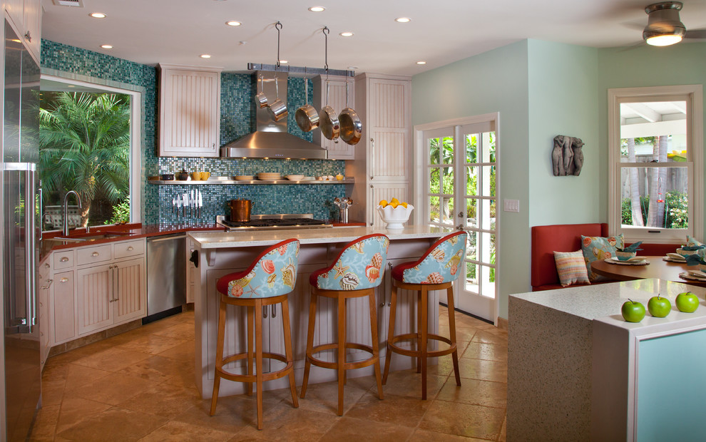 Photo of a mid-sized tropical l-shaped eat-in kitchen in San Diego with an undermount sink, recessed-panel cabinets, white cabinets, blue splashback, mosaic tile splashback, stainless steel appliances, with island and recycled glass benchtops.