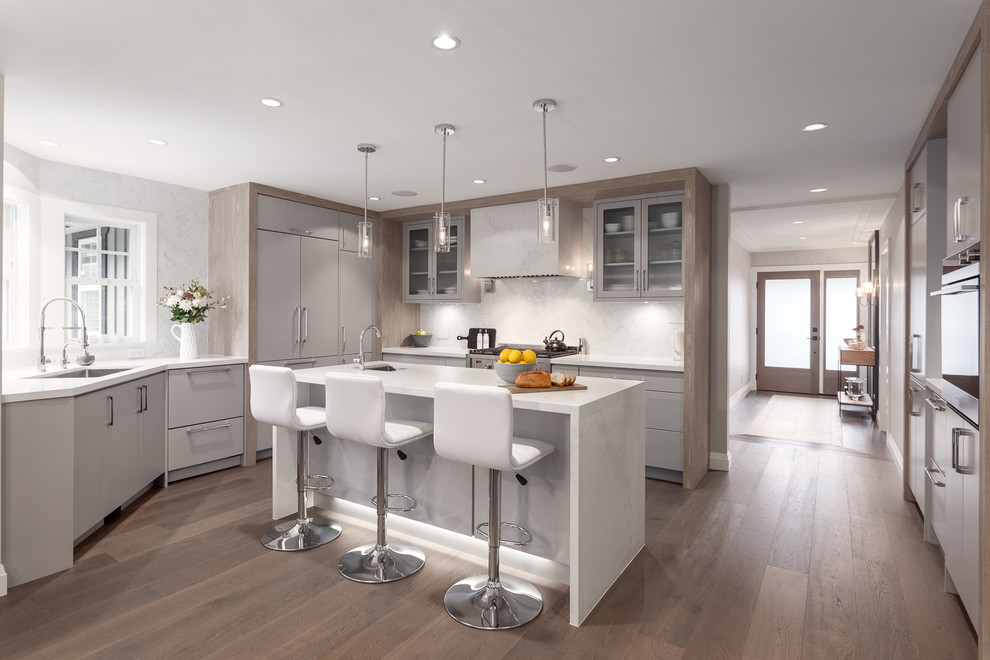 This is an example of a mid-sized contemporary u-shaped kitchen in Vancouver with an undermount sink, flat-panel cabinets, grey cabinets, marble benchtops, white splashback, with island, brown floor, panelled appliances, dark hardwood floors and marble splashback.