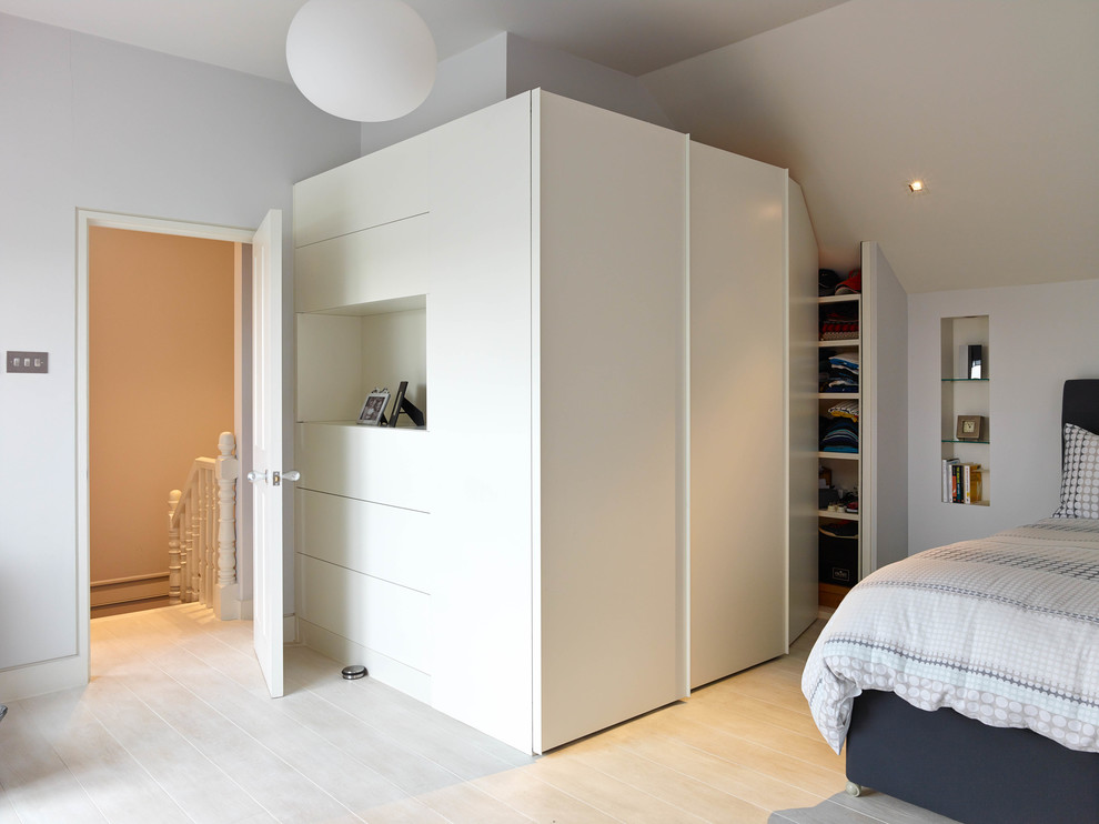 Design ideas for a large contemporary guest bedroom in London with white walls, light hardwood floors and no fireplace.