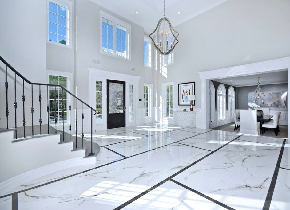 Photo of an expansive transitional foyer in Los Angeles with marble floors, a single front door, a black front door, multi-coloured floor and grey walls.