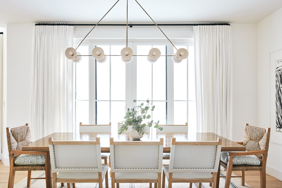 Photo of a transitional separate dining room in Los Angeles with white walls, light hardwood floors and beige floor.