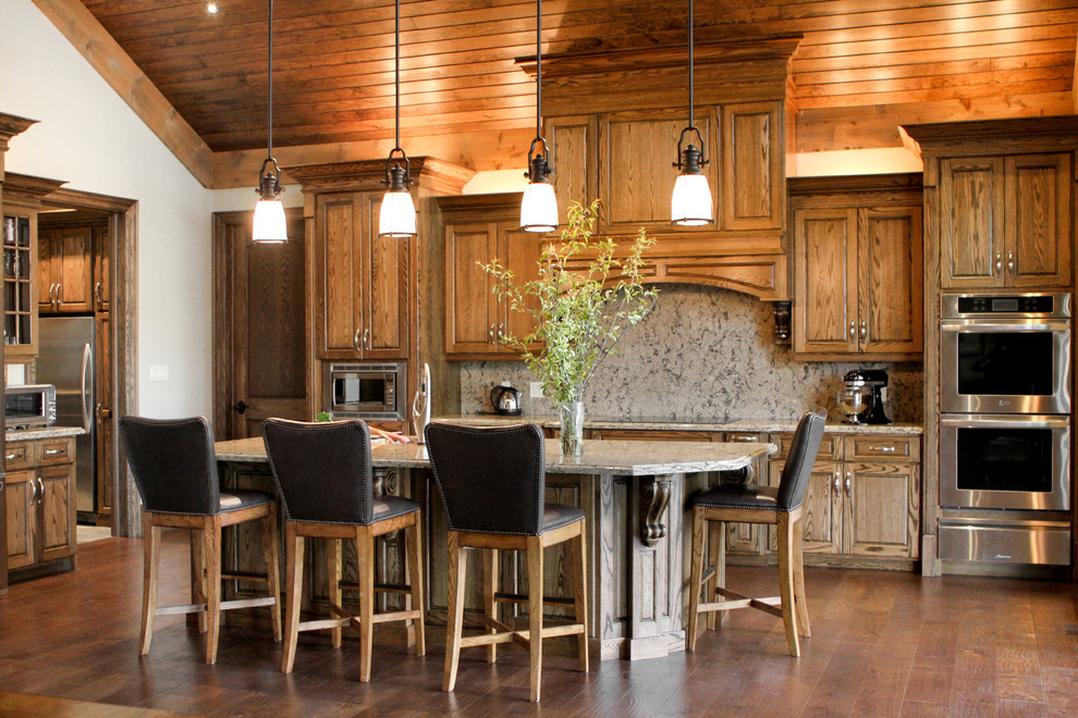Mid-sized mountain style l-shaped medium tone wood floor open concept kitchen photo in Toronto with an undermount sink, raised-panel cabinets, medium tone wood cabinets, granite countertops, multicolored backsplash, stone slab backsplash, stainless steel appliances and an island