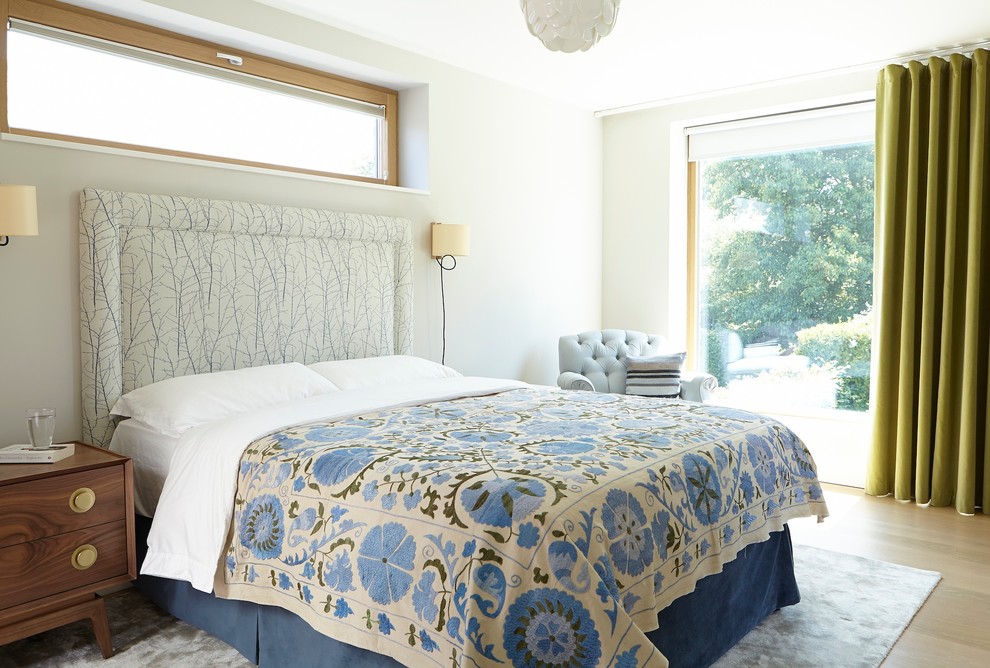 Small contemporary bedroom in Dublin with white walls, light hardwood floors and beige floor.