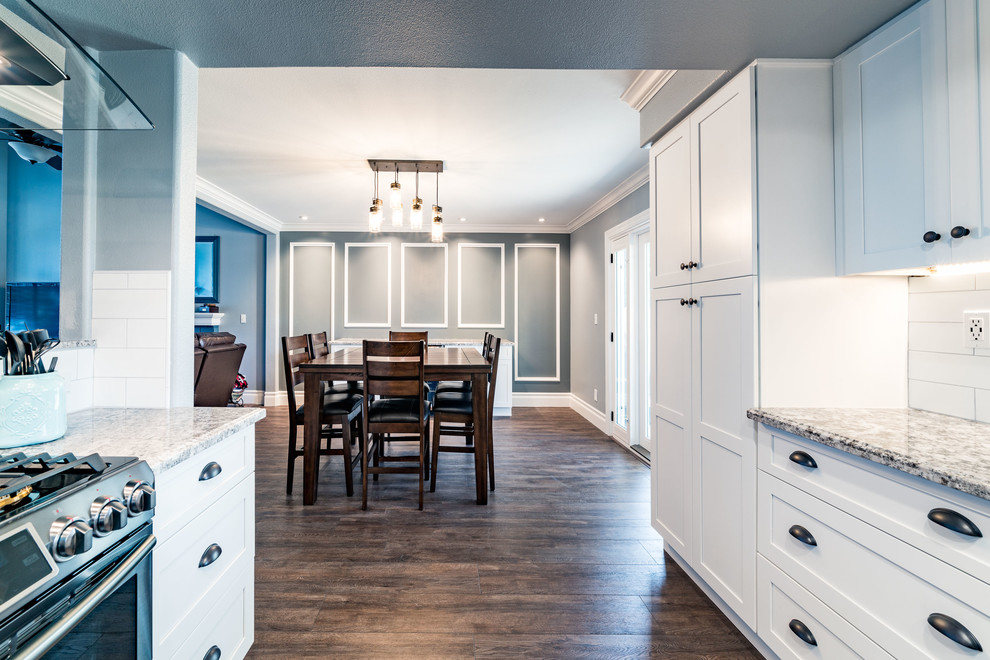 Eat-in kitchen - mid-sized transitional u-shaped dark wood floor and brown floor eat-in kitchen idea with an undermount sink, shaker cabinets, white cabinets, granite countertops, white backsplash, subway tile backsplash, stainless steel appliances and an island
