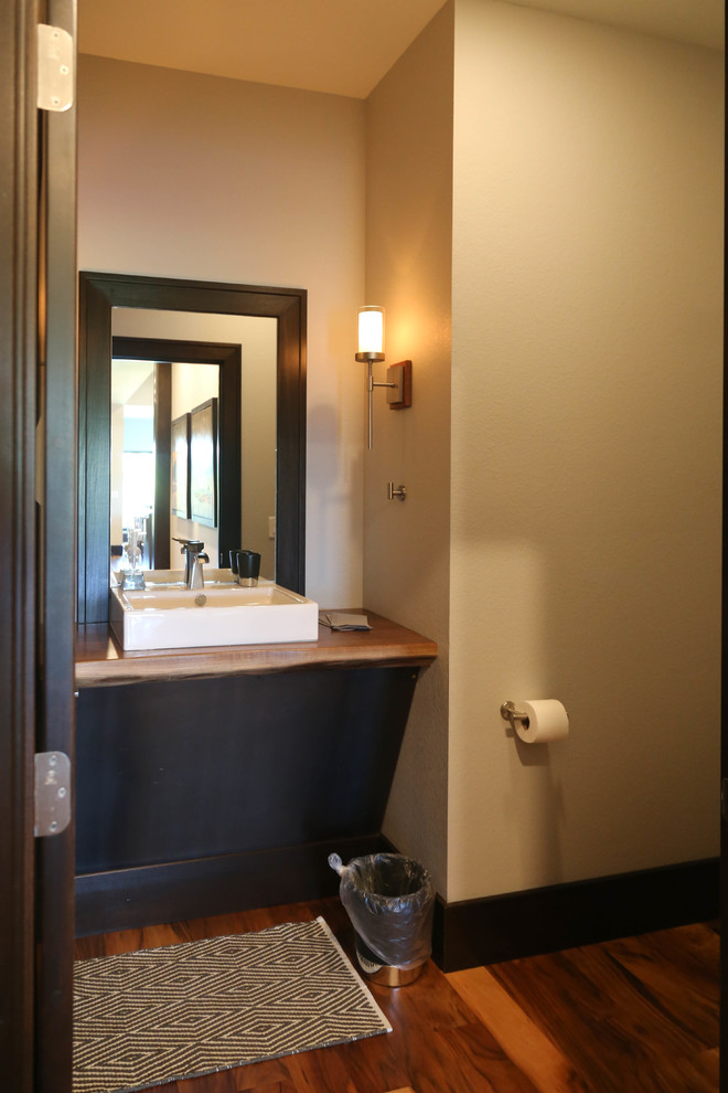Example of a large transitional 3/4 medium tone wood floor and brown floor home design design with a two-piece toilet, white walls, a vessel sink and wood countertops
