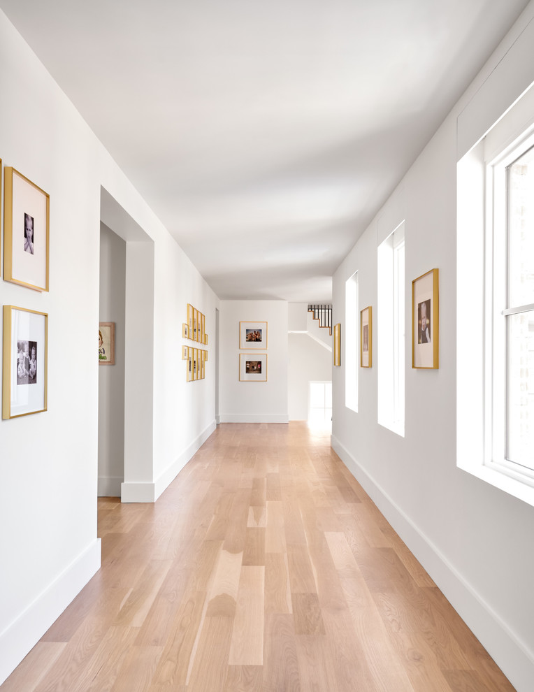 This is an example of a large transitional hallway in Dallas with white walls, medium hardwood floors and brown floor.