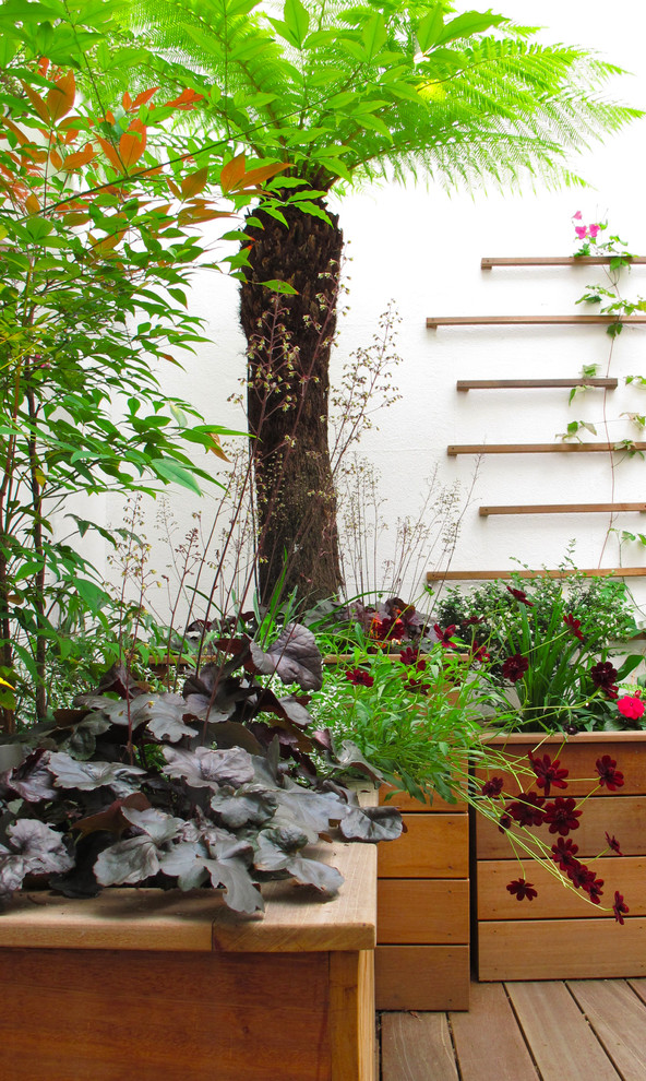 Small traditional courtyard partial sun garden in London with a container garden and decking for spring.