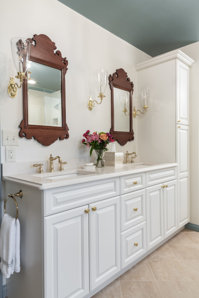 Design ideas for a large traditional master bathroom in St Louis with raised-panel cabinets, white cabinets, a freestanding tub, a corner shower, white tile, subway tile, blue walls, porcelain floors, an undermount sink, engineered quartz benchtops, beige floor, a hinged shower door and white benchtops.