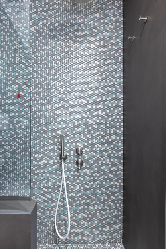 Идея дизайна: маленькая ванная комната в стиле модернизм с душем в нише, раздельным унитазом, серой плиткой, плиткой мозаикой, серыми стенами, бетонным полом, настольной раковиной, столешницей из искусственного камня, серым полом, душем с распашными дверями, черной столешницей, сиденьем для душа и тумбой под одну раковину для на участке и в саду