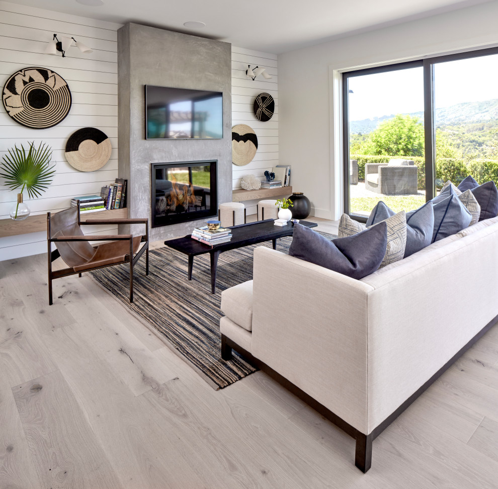 Design ideas for a contemporary living room in San Francisco with white walls, light hardwood floors, a standard fireplace, a concrete fireplace surround, a wall-mounted tv and beige floor.