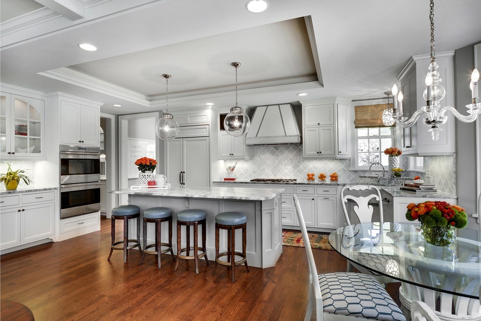 Design ideas for a transitional eat-in kitchen in Minneapolis with recessed-panel cabinets, white cabinets, grey splashback and white appliances.