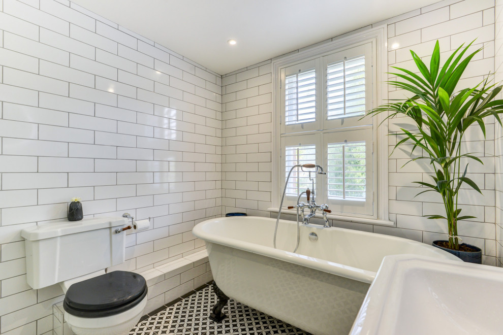 Mid-sized ornate kids' white tile and ceramic tile ceramic tile, multicolored floor and single-sink bathroom photo in Sussex with a two-piece toilet, white walls, a pedestal sink, tile countertops and black countertops