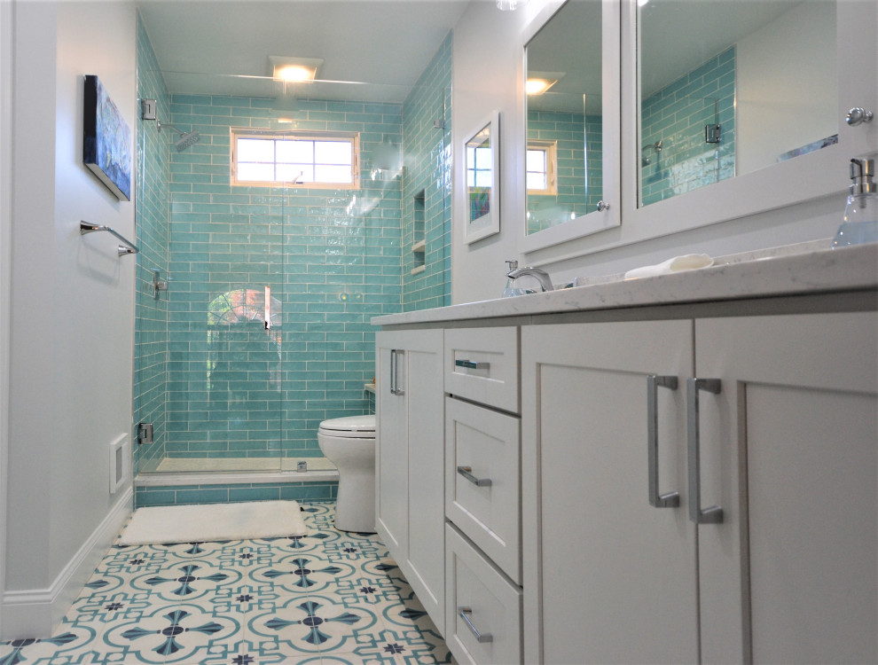 На фото: большая главная ванная комната в стиле неоклассика (современная классика) с фасадами в стиле шейкер, белыми фасадами, угловым душем, унитазом-моноблоком, зеленой плиткой, цементной плиткой, белыми стенами, полом из линолеума, врезной раковиной, столешницей из искусственного кварца, разноцветным полом, душем с распашными дверями, белой столешницей, нишей, тумбой под две раковины и встроенной тумбой