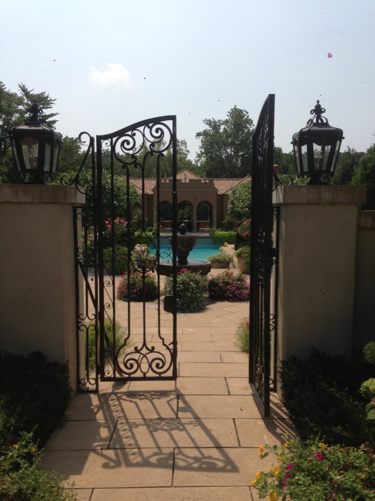 Example of a large tuscan backyard concrete paver patio fountain design in St Louis with no cover
