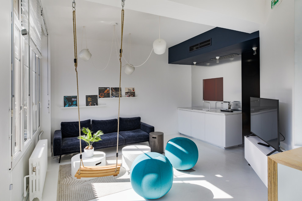 This is an example of a contemporary open concept living room in Paris with concrete floors, a wall-mounted tv and white floor.