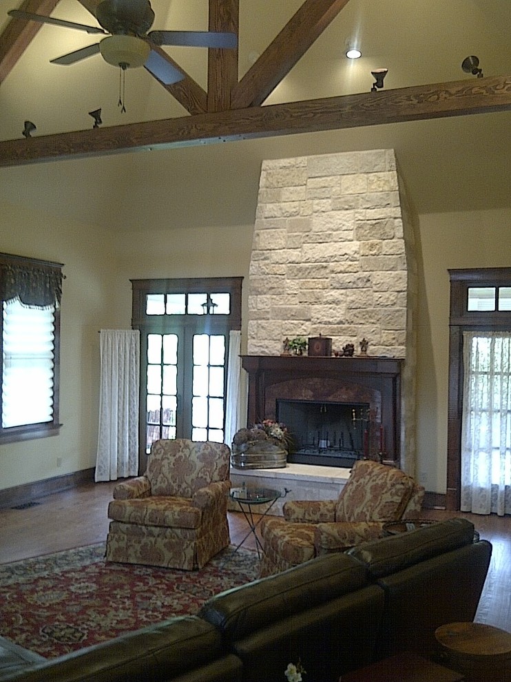 Inspiration for a large transitional enclosed family room in Austin with yellow walls, medium hardwood floors, a standard fireplace, a stone fireplace surround and a wall-mounted tv.