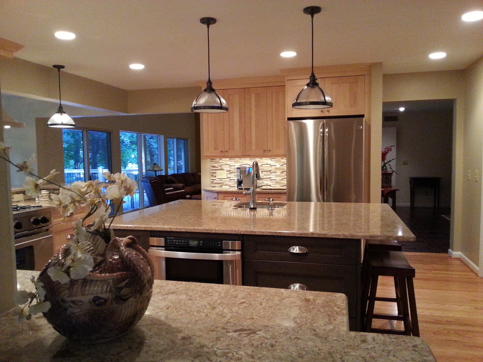 Example of a mid-sized transitional l-shaped medium tone wood floor kitchen pantry design in New York with an undermount sink, raised-panel cabinets, light wood cabinets, beige backsplash, stone slab backsplash, stainless steel appliances and an island