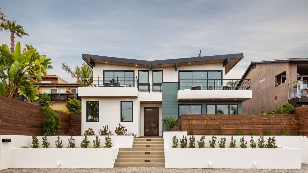 This is an example of a large contemporary two-storey white house exterior in San Diego with a shed roof.