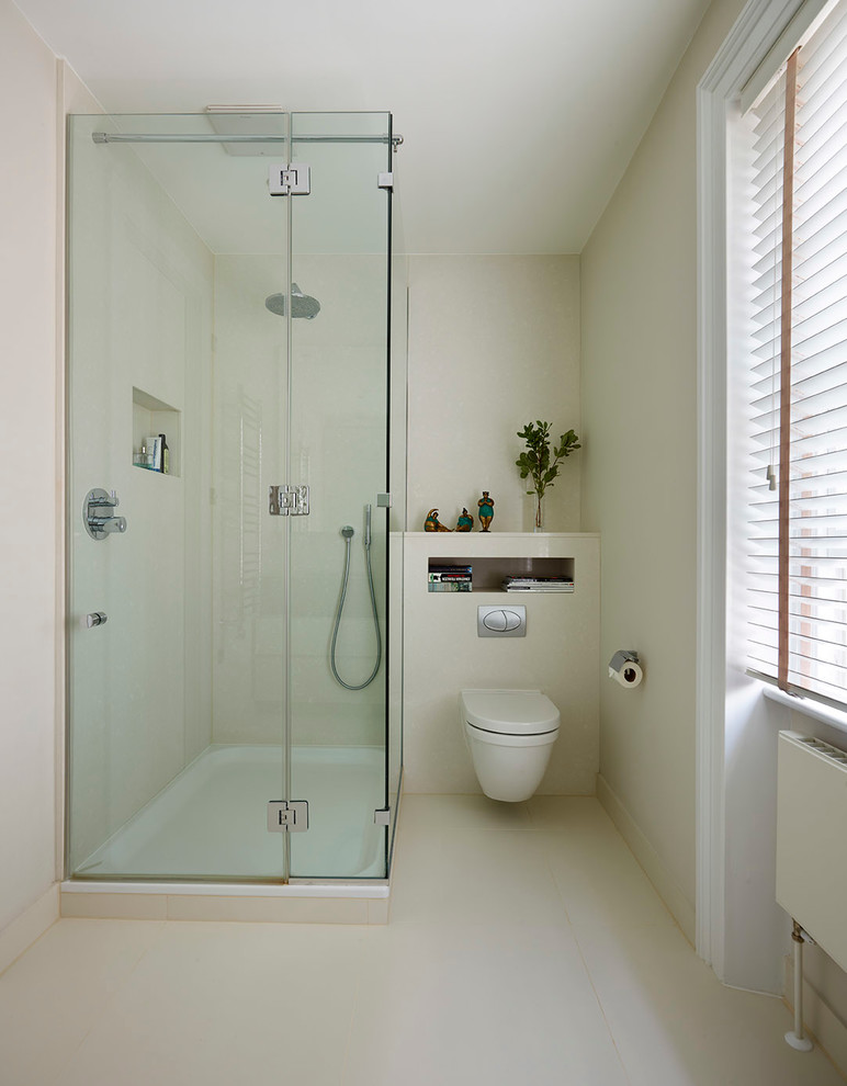 This is an example of a small traditional master bathroom in London with furniture-like cabinets, white cabinets, a corner shower, a wall-mount toilet, white tile, porcelain tile, white walls and porcelain floors.