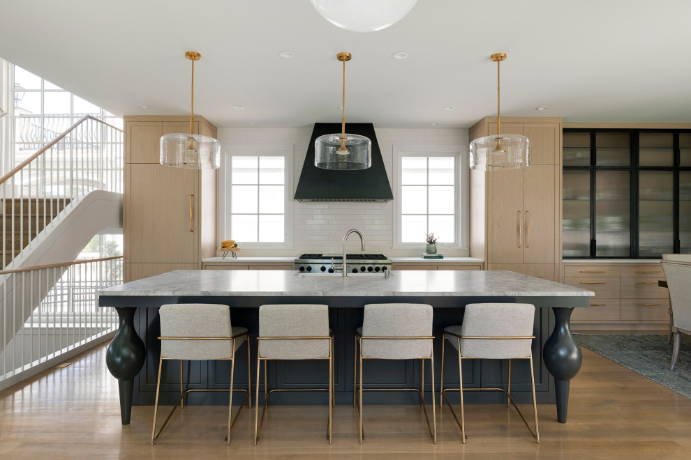 Design ideas for a large classic kitchen/diner in Minneapolis with a belfast sink, beaded cabinets, light wood cabinets, marble worktops, beige splashback, ceramic splashback, integrated appliances, light hardwood flooring, an island and grey worktops.