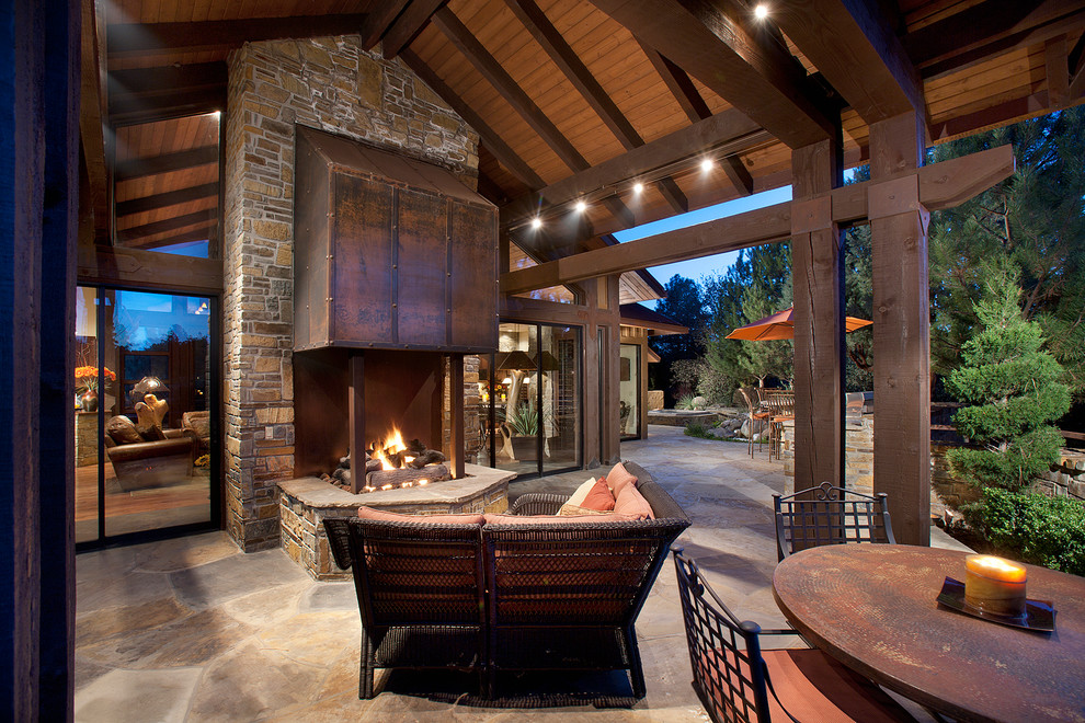 Design ideas for a mid-sized country backyard patio in Phoenix with a fire feature, natural stone pavers and a roof extension.