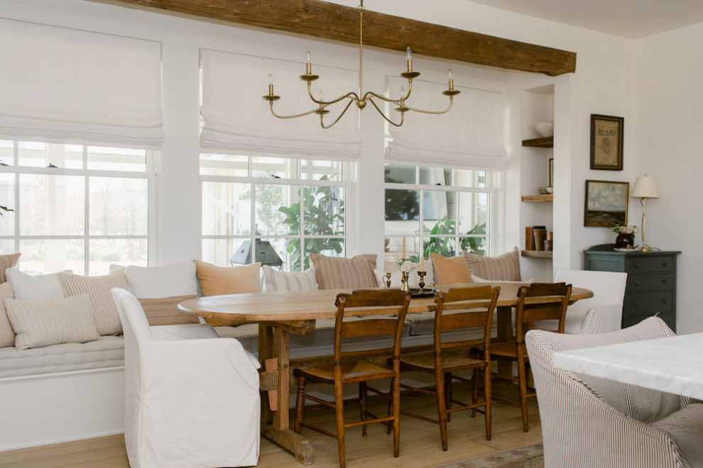 Cette image montre une salle à manger ouverte sur la cuisine rustique de taille moyenne avec un mur blanc, parquet clair, aucune cheminée, un sol marron et poutres apparentes.