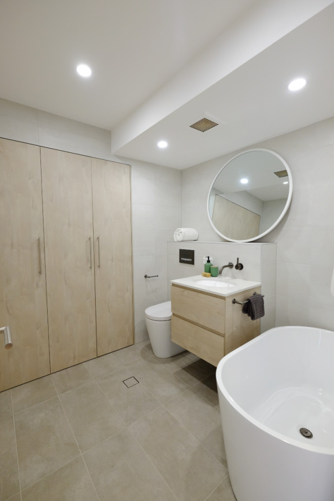 Example of a small urban white tile and porcelain tile porcelain tile, gray floor and single-sink bathroom design in Sydney with flat-panel cabinets, light wood cabinets, a wall-mount toilet, white walls, a drop-in sink, quartzite countertops, white countertops and a floating vanity