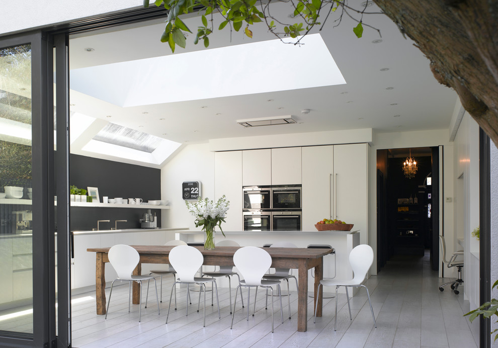 Design ideas for a large contemporary l-shaped eat-in kitchen in London with flat-panel cabinets, white cabinets, quartz benchtops and an undermount sink.