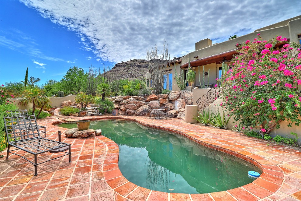Inspiration for a mid-sized traditional backyard custom-shaped pool in Phoenix with natural stone pavers.
