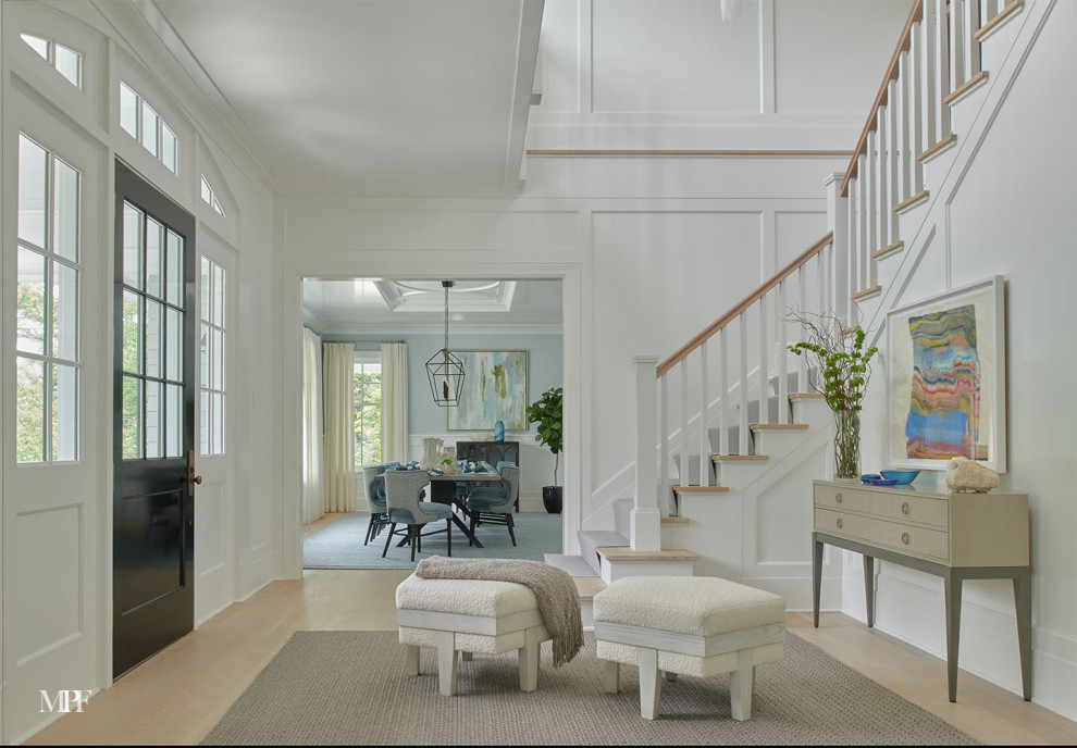 This is an example of a transitional entryway in New York with white walls, light hardwood floors, a single front door and a black front door.