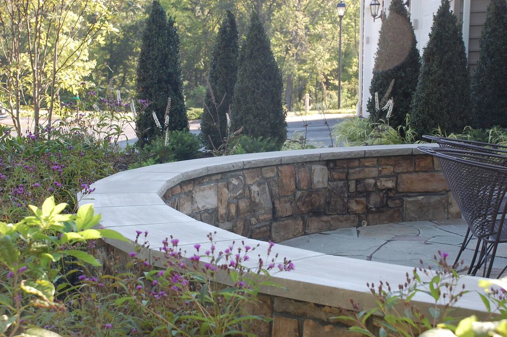 This is an example of a mid-sized transitional partial sun backyard stone landscaping in DC Metro.