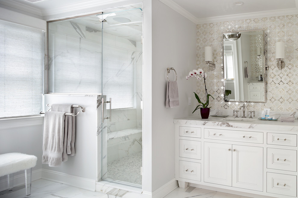 Photo of a large traditional master bathroom in New York with recessed-panel cabinets, white cabinets, a corner shower, a one-piece toilet, white tile, marble, white walls, marble floors, an undermount sink, marble benchtops, white floor and a hinged shower door.