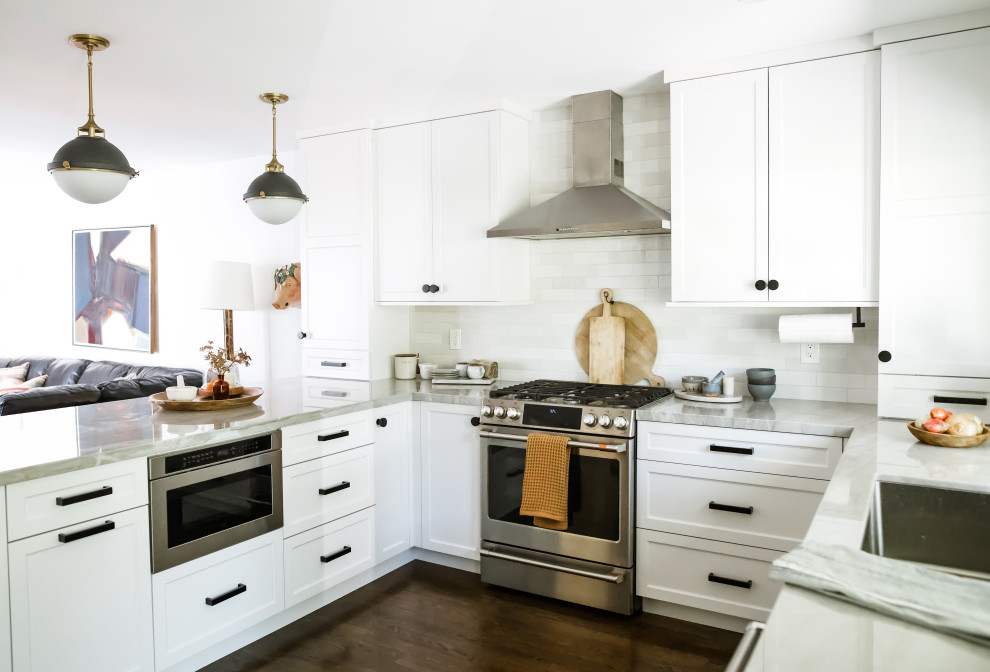 Inspiration for a mid-sized transitional u-shaped separate kitchen in San Francisco with an undermount sink, shaker cabinets, white cabinets, solid surface benchtops, white splashback, ceramic splashback, stainless steel appliances, medium hardwood floors, no island, brown floor and grey benchtop.