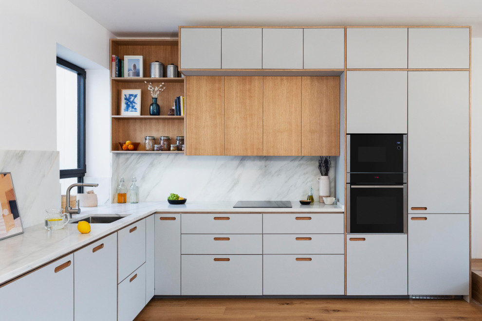 Photo of a mid-sized contemporary l-shaped open plan kitchen in Madrid with an undermount sink, shaker cabinets, light wood cabinets, granite benchtops, grey splashback, granite splashback, panelled appliances, medium hardwood floors, no island, brown floor and grey benchtop.