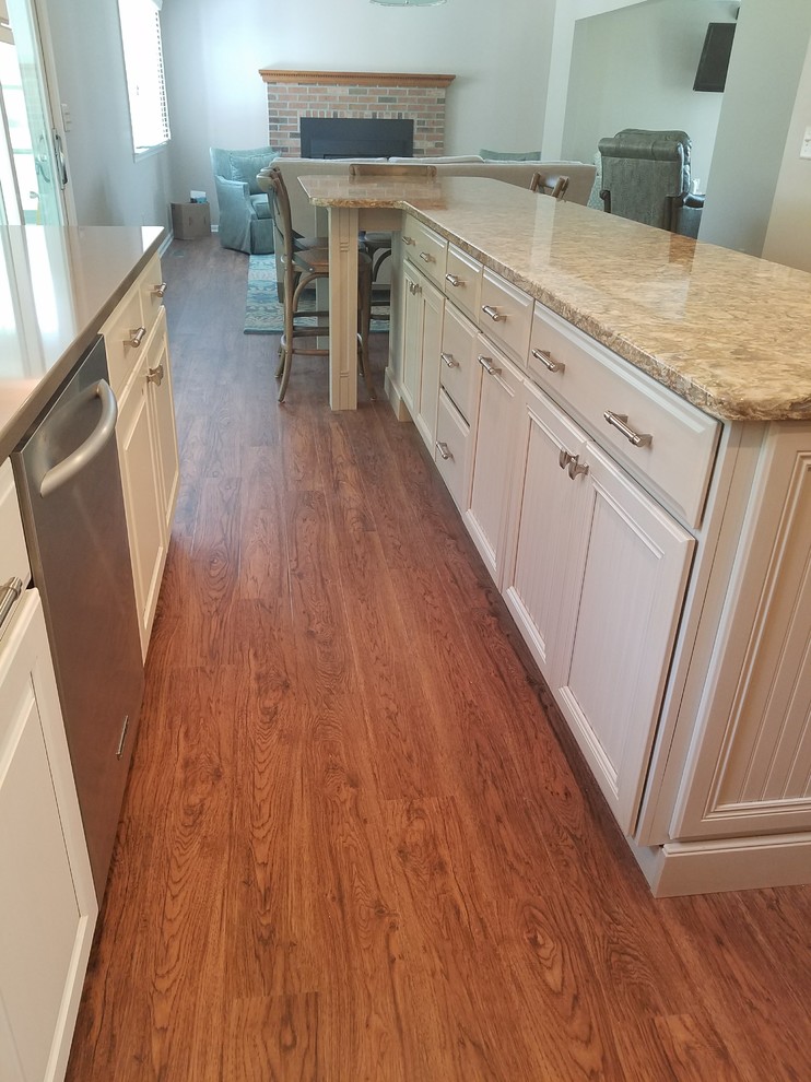 Open concept kitchen - mid-sized transitional l-shaped dark wood floor open concept kitchen idea in Baltimore with an undermount sink, raised-panel cabinets, white cabinets, granite countertops, metallic backsplash, matchstick tile backsplash, stainless steel appliances and an island