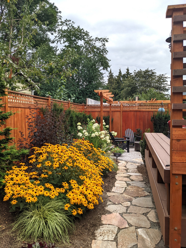 Immagine di un piccolo giardino xeriscape stile americano esposto in pieno sole dietro casa in estate con un ingresso o sentiero, pavimentazioni in pietra naturale e recinzione in legno