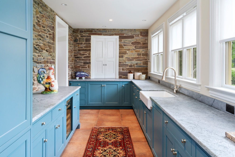 Large country l-shaped separate kitchen in Philadelphia with a farmhouse sink, beaded inset cabinets, blue cabinets, soapstone benchtops, blue splashback, ceramic splashback, panelled appliances, porcelain floors, with island, orange floor, black benchtop and recessed.