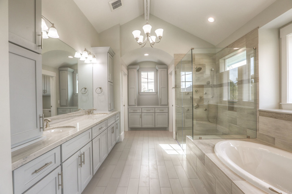 Example of a mid-sized transitional white tile and ceramic tile ceramic tile and gray floor drop-in bathtub design in Houston with shaker cabinets, white cabinets, a two-piece toilet, white walls, an undermount sink, granite countertops and a hinged shower door