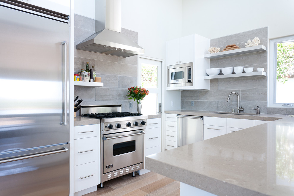 Inspiration for a contemporary u-shaped kitchen in Orange County with white cabinets, grey splashback, porcelain splashback and stainless steel appliances.