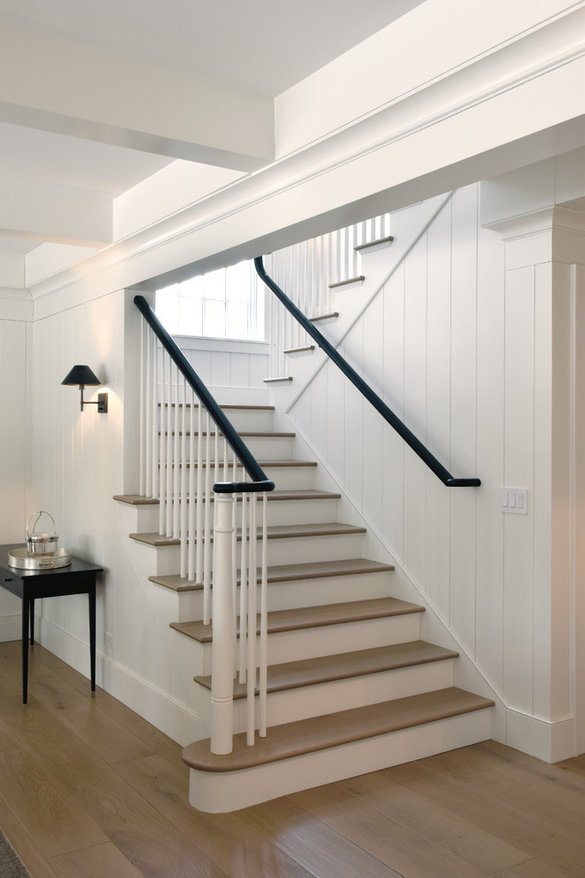 Photo of a large scandinavian wood u-shaped staircase in Chicago with wood risers, wood railing and planked wall panelling.