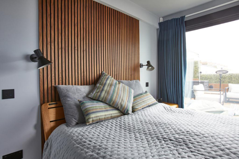 Mittelgroßes Retro Hauptschlafzimmer mit blauer Wandfarbe, Teppichboden, beigem Boden und Wandpaneelen in Sussex